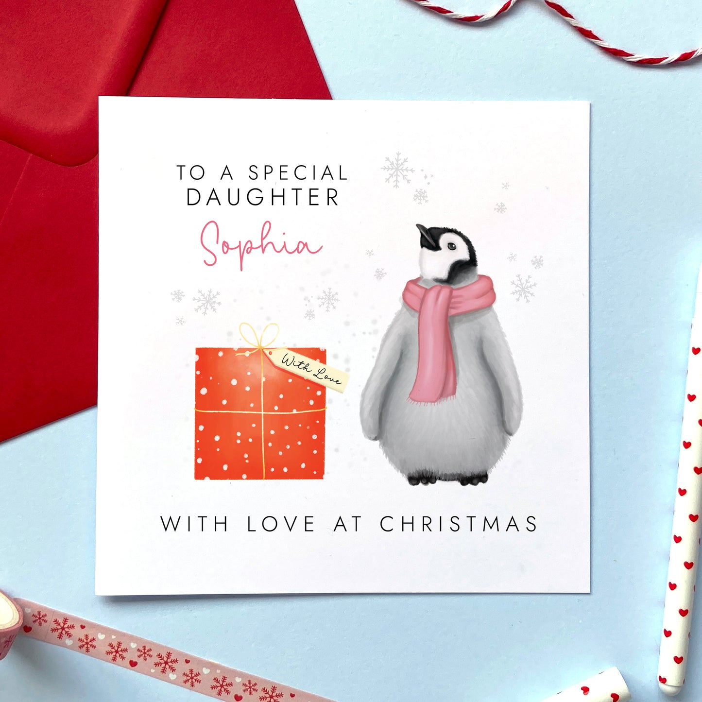 A personalised Christmas card for Girl featuring a baby penguin in a pink scarf. It can be personalised with a name. The card in the photo is a Christmas Card for Daughter.