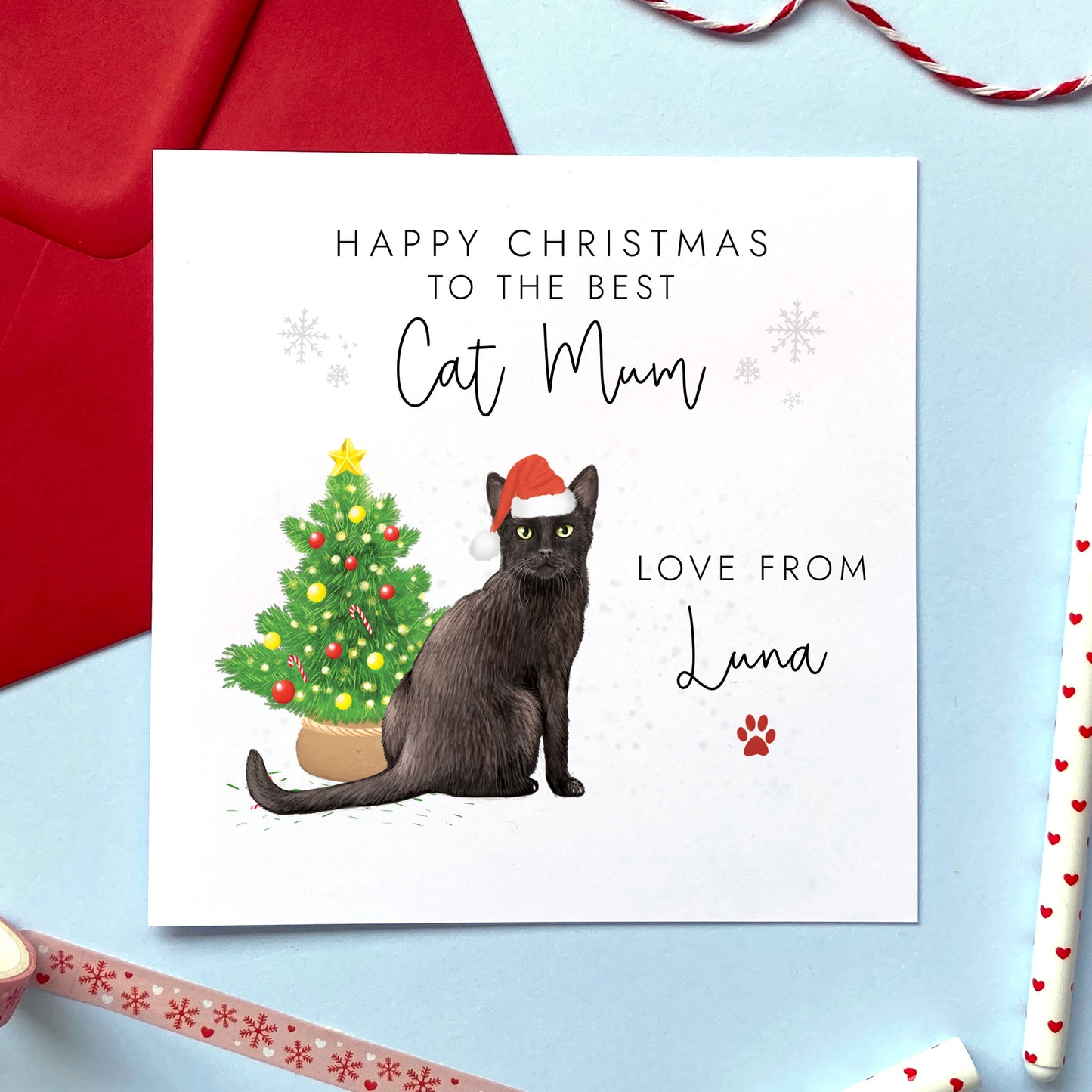 A personalised Christmas card for Cat Mum featuring a black cat wearing a santa hat next to a christmas tree. It features the text 'Happy Christmas to the best Cat Mum' and can be personalised with the cat's name.