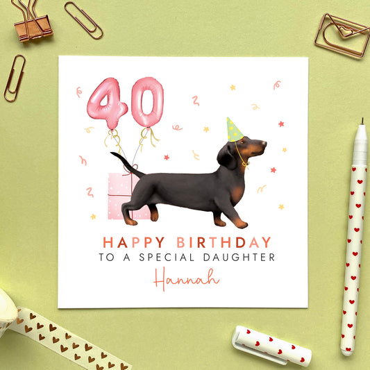 A personalised dog birthday card for her featuring a black and tan sausage dog (Dachshund). It can be personalised with any name and age. The card in the photo is a 40th birthday card for Daughter.
