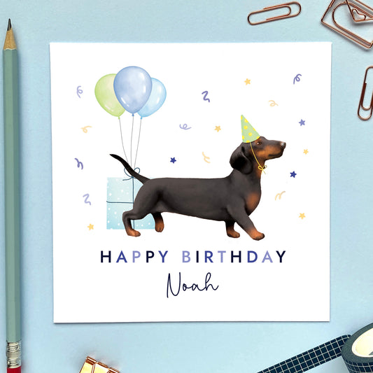 A personalised dog birthday card for him featuring a black and tan sausage dog (Dachshund). It can be personalised with any name and age.
