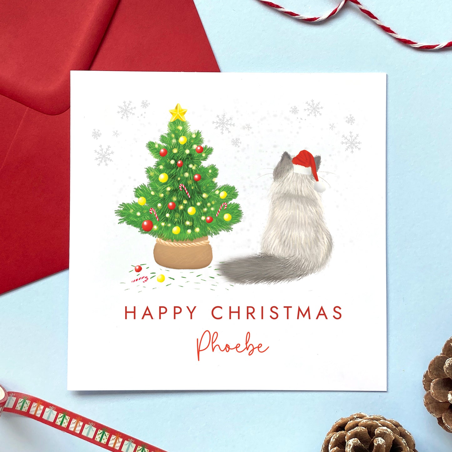 A personalised cat christmas card. You can choose the cat on the design from a wide range of options, examples include ginger cat, black cat, ragdoll cat, tabby cat and grey cat. It can be personalised by adding a name and any relation. The card in the photo is a ragdoll cat christmas card.