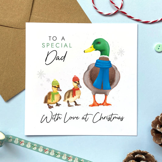 A personalised ducks christmas card for Dad. It features a male mallard duck next to two baby ducklings or children, with the text 'To a special Dad, with love at Christmas'.