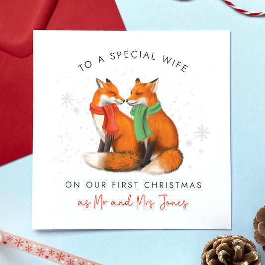 A personalised On Our First Christmas as Mr and Mrs Christmas card featuring a fox couple. It can be personalised with a surname, and is for couples who are celebrating 'our 1st christmas as a married couple'. The card in the photo is a Christmas Card for Wife.