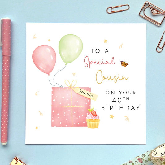 A pink themed birthday card for Cousin featuring a pink present and strawberry cupcake, with balloons. It can be personalised with a name and any age, including 18th, 21st, 30th and 40th. It's a card for female cousins. The card in the photo is for 40th birthday.