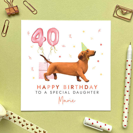 A personalised dog birthday card for her featuring a brown sausage dog (Dachshund). It can be personalised with any name and age. The card in the photo is a 40th birthday card for Daughter.