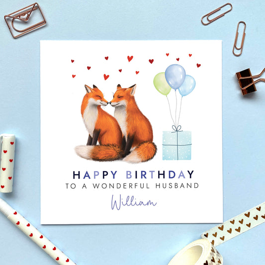 A personalised birthday card for him featuring a fox couple. It can be personalised with any relation, age and name. The card in the photo is a birthday card for Husband.