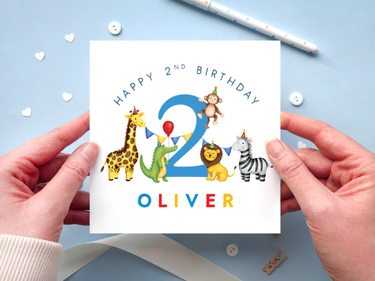 a personalised safari themed birthday card for boys, featuring illustrations of jungle animals - giraffe, crocodile, lion, zebra and monkey - around the number 2, in bright and bold colours