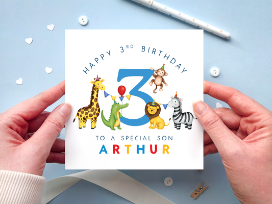 A personalised safari themed 3rd birthday card for boys, featuring illustrations of jungle animals - giraffe, crocodile, lion, zebra and monkey - around the number 3, in bright and bold colours