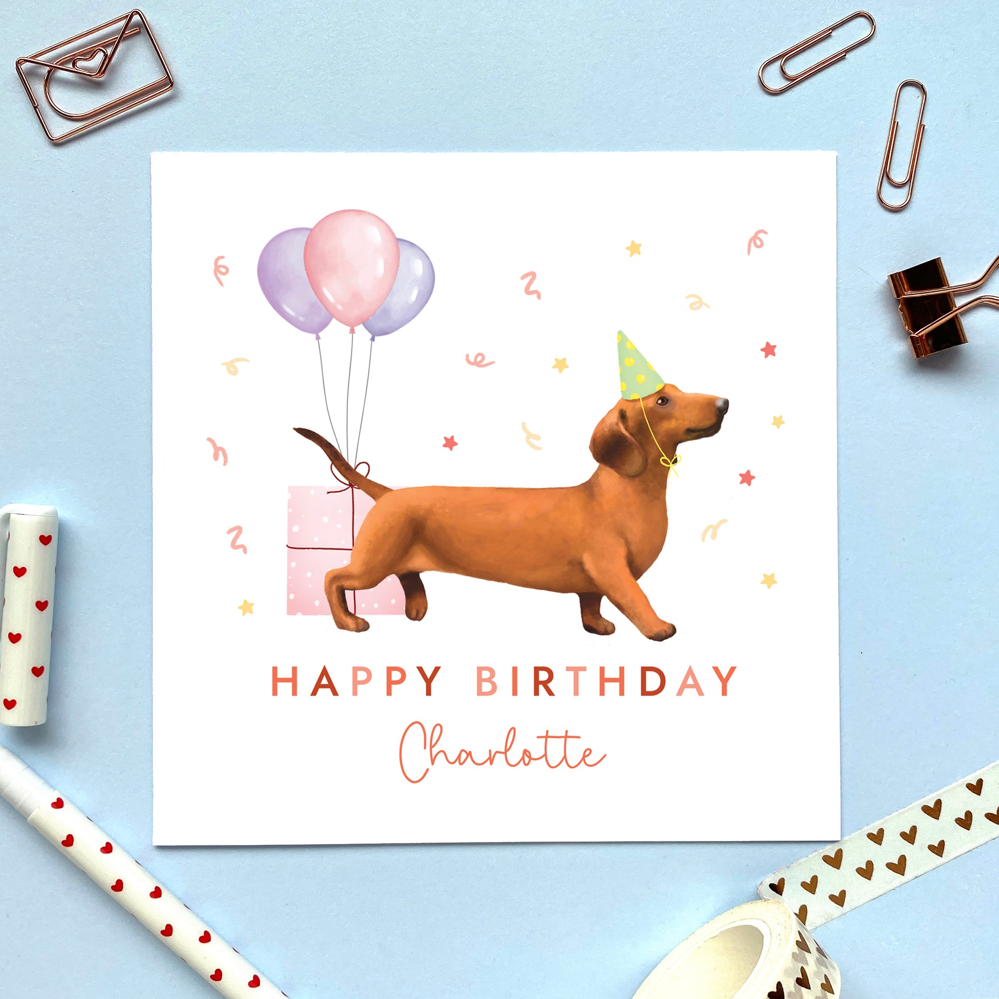 A personalised dog birthday card for her featuring a brown sausage dog (Dachshund). It can be personalised with any name and age. The card in the photo is for a lady.