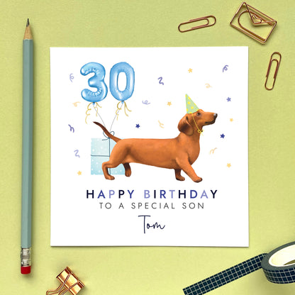 A personalised dog birthday card for him featuring a sausage dog (Dachshund). It can be personalised with any name and age. The card in the photo is a 30th birthday card for son.
