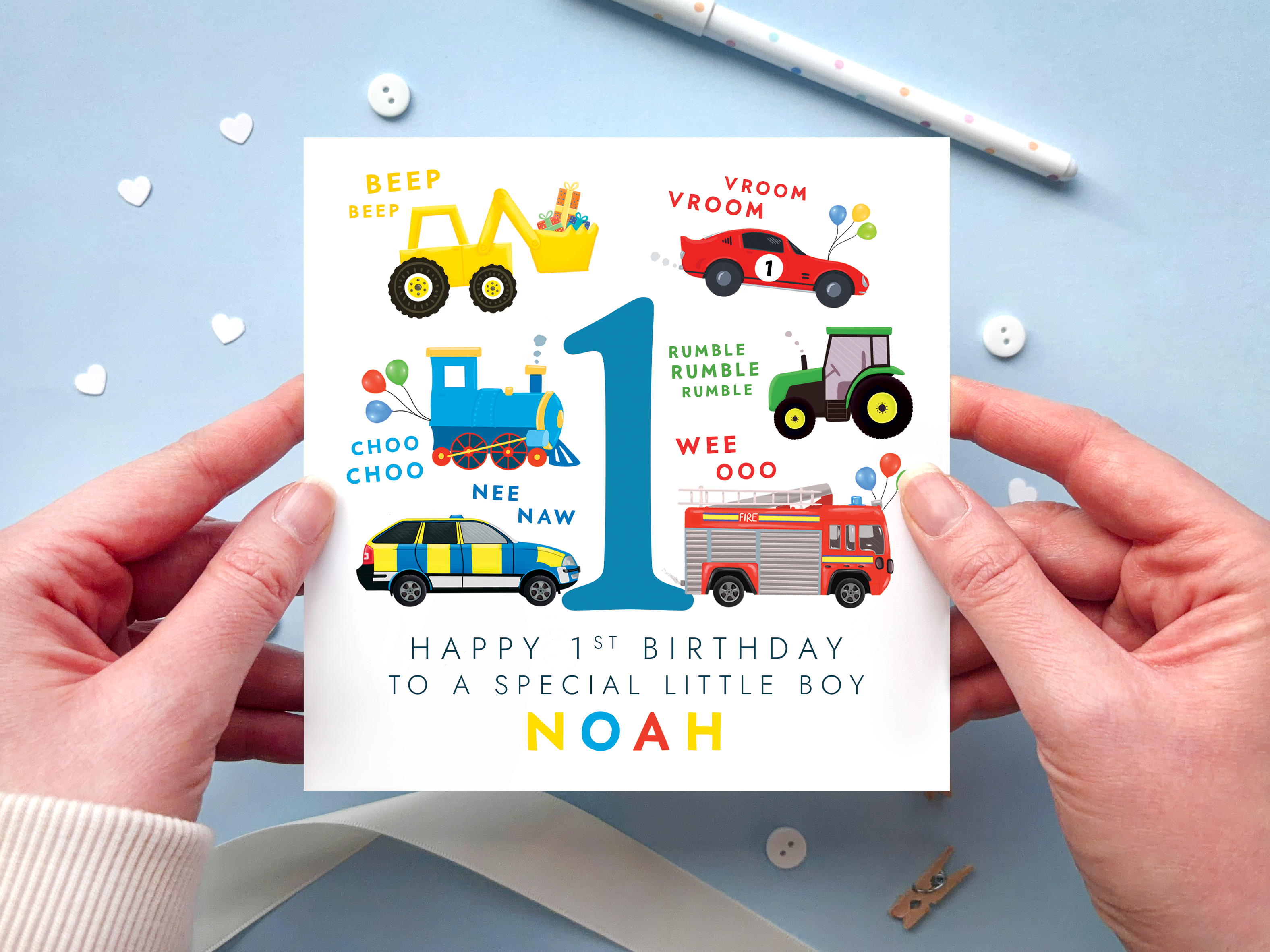personalised transportation themed 1st birthday card featuring colourful vehicles: yellow digger, red race car, blue train, green tractor, police car and fire engine around the number 1