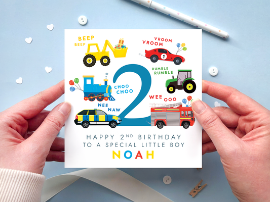 personalised transportation themed 2nd birthday card featuring colourful vehicles: yellow digger, red race car, blue train, green tractor, police car and fire engine around the number 2