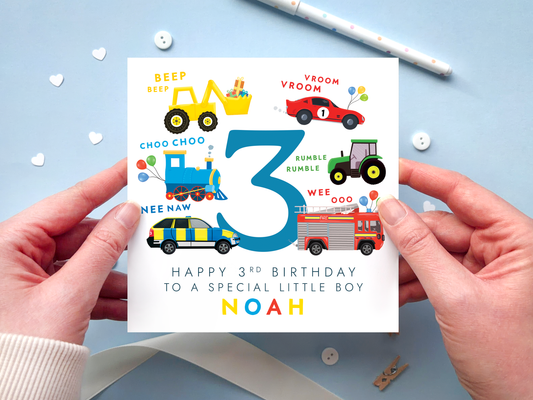 personalised transportation themed 3rd birthday card featuring colourful vehicles: yellow digger, red race car, blue train, green tractor, police car and fire engine around the number 3